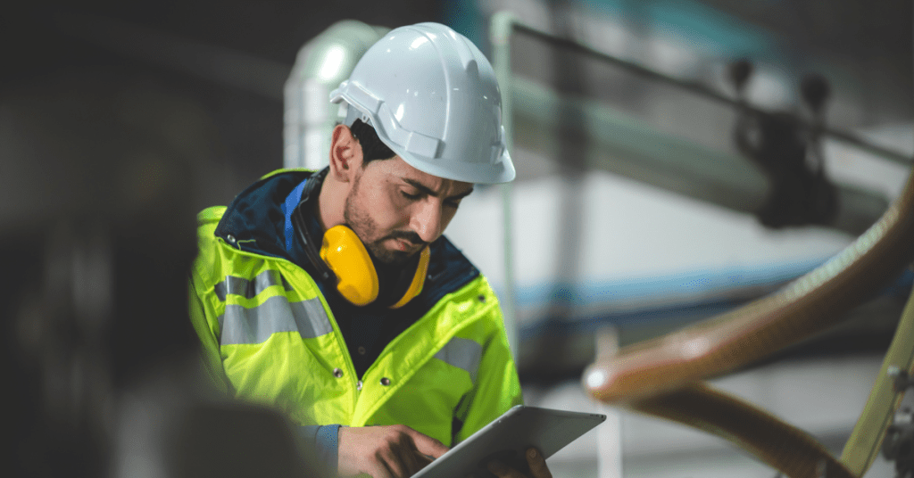 a man wearing a hard hat looking at his tablet