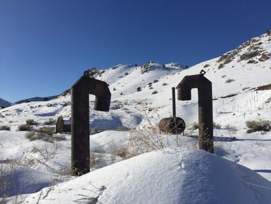 A close-up of two exposed, curved pipes emerging from the snow.