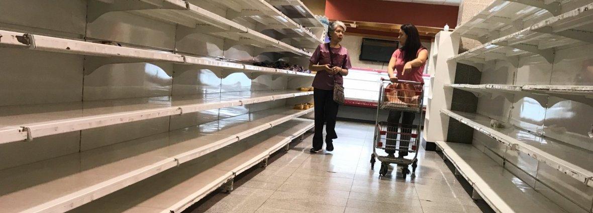 People walk past empty shelves