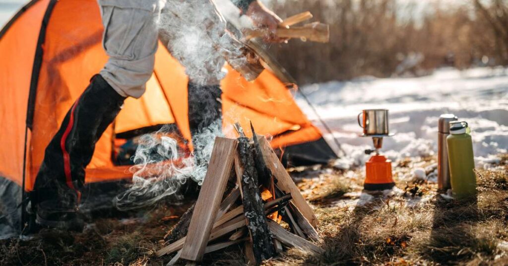 a man putting wood for his camp fire