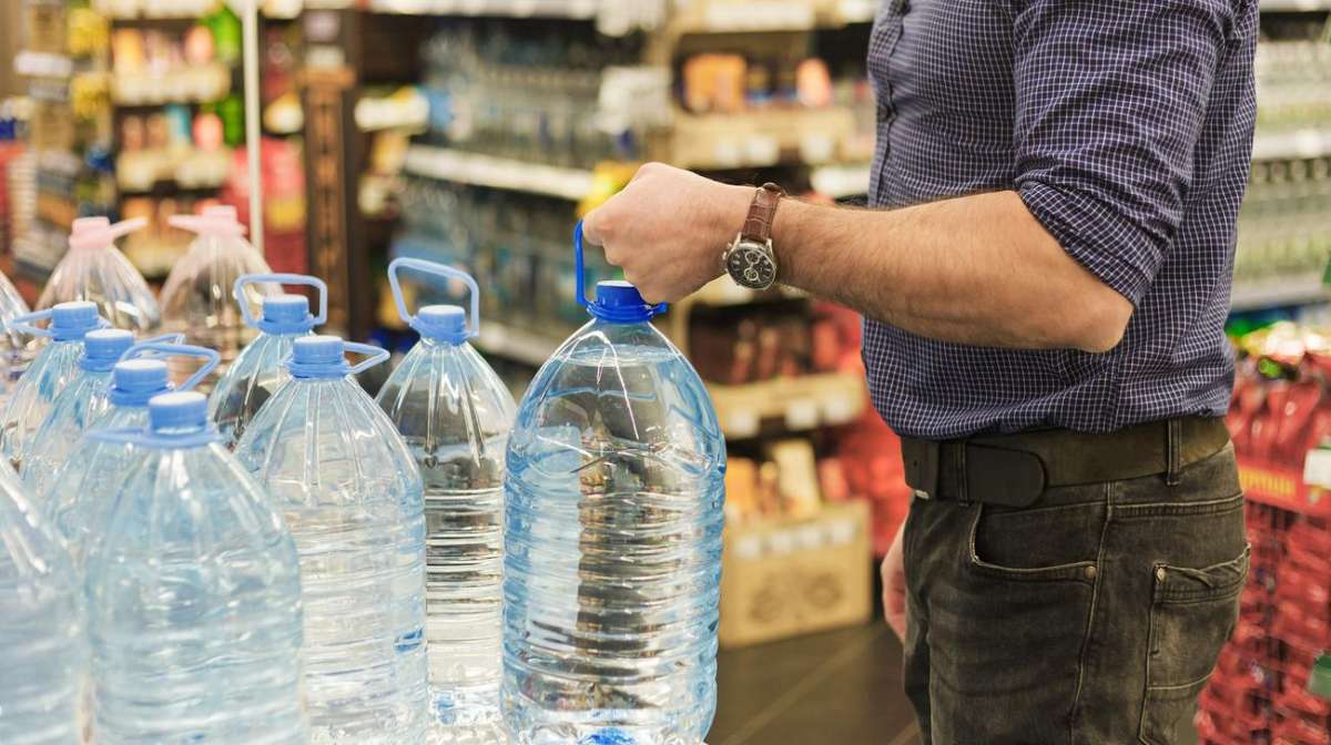 A man holding a bottle of distilled water in the supermarket. 