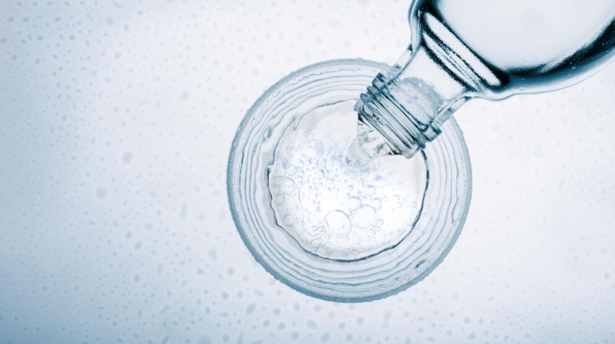 A glass bottle pouring fresh water on a glass. 