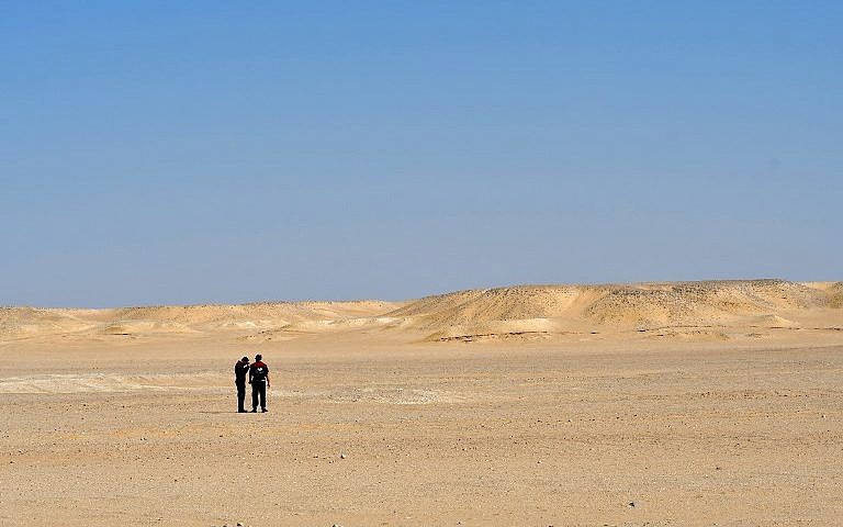 Two men standing in the middle of the desert. 