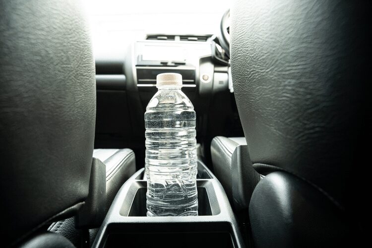 A bottled water inside the car's cup holder. 