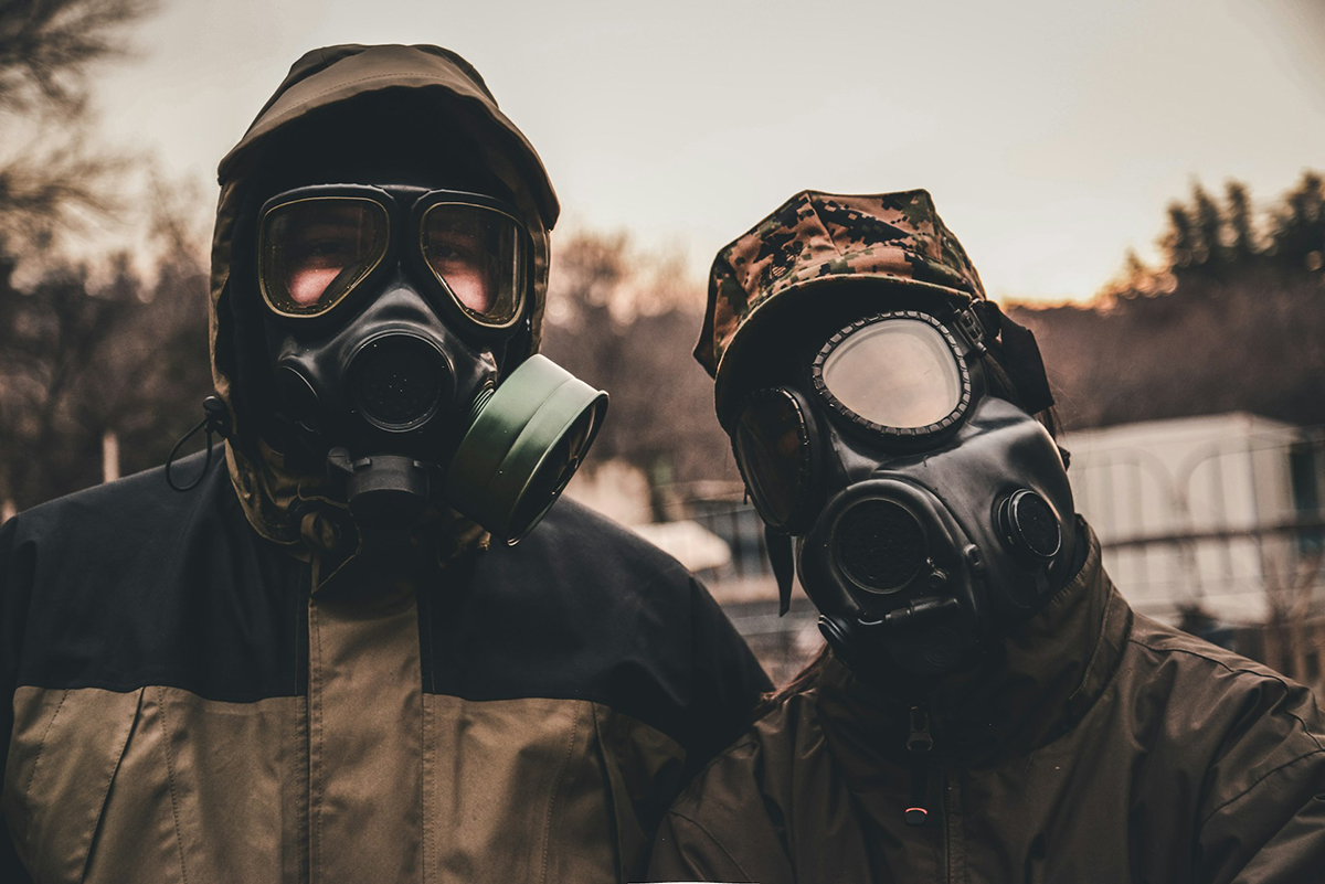 Two men wearing gas masks and PPEs.