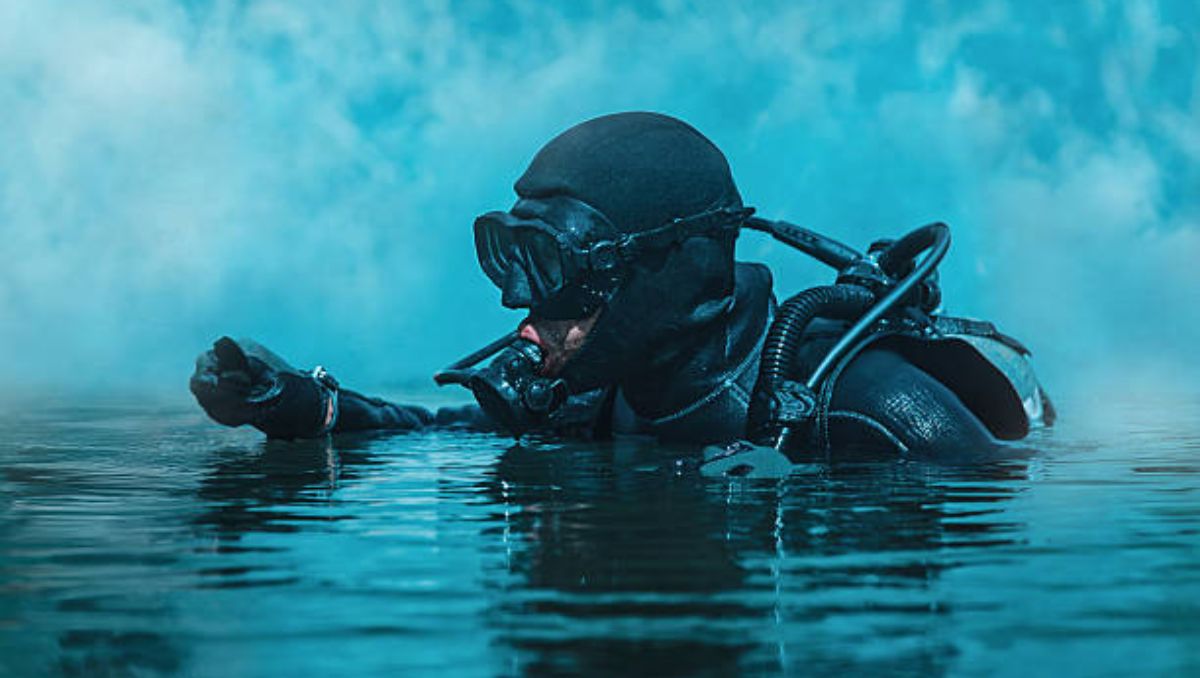 A navy SEAL wearing a gas mask in the water.