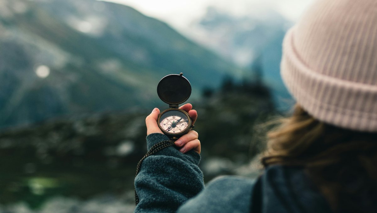 A woman holding a compass in the wilderness.