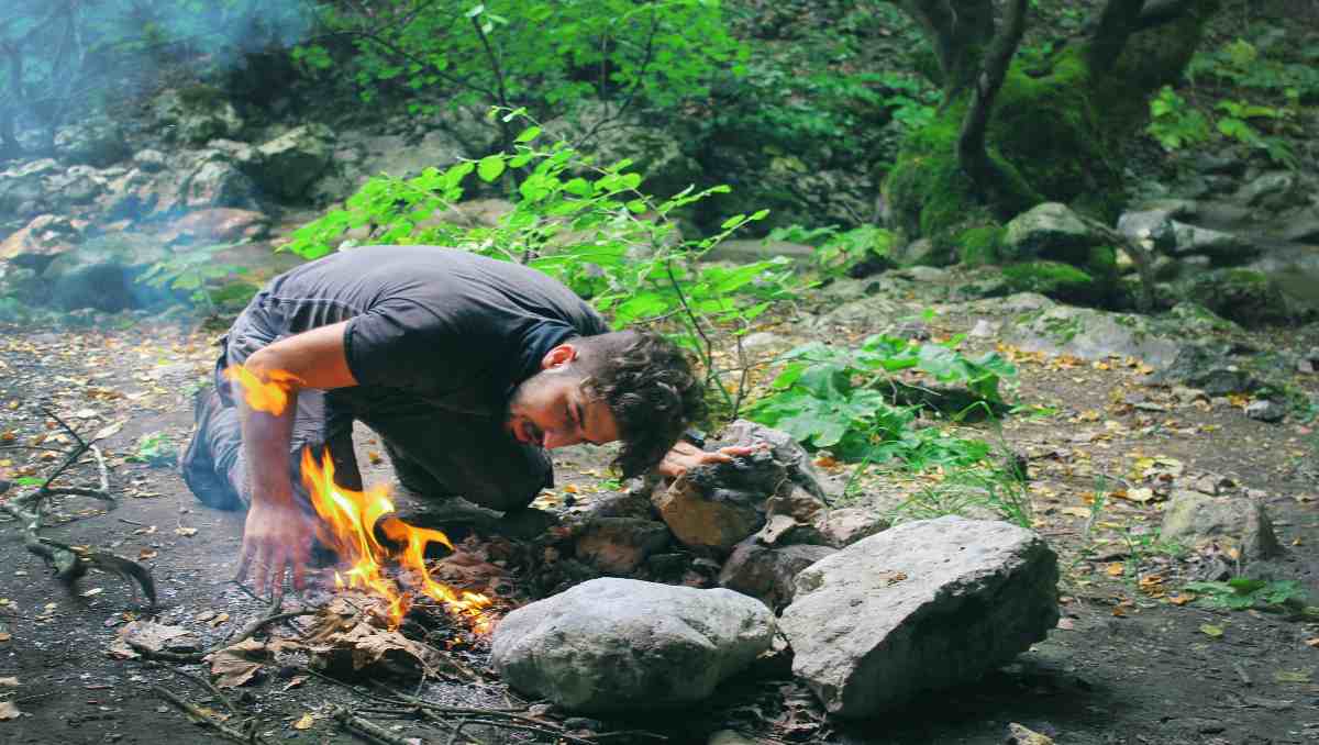 A prepper making a fire in the woods.